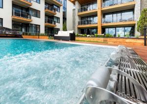 ein Pool mit einer Bank neben einem Gebäude in der Unterkunft Apartmán B 101 Vysoké Tatry in Starý Smokovec