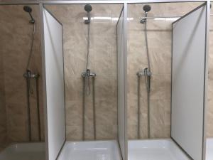 a bathroom with two shower doors and a tub at ГотельОК Видубичі in Kyiv