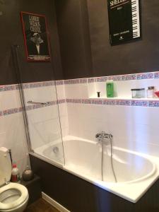 a bathroom with a bath tub and a toilet at La Maison in Les Forges