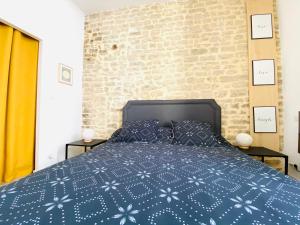 a bedroom with a blue bed with a brick wall at Feel@Home Nemausus « Le 4 » in Nîmes