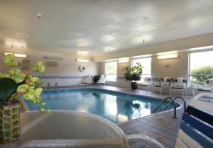 una piscina en una habitación de hotel con sillas y mesas en AmericInn by Wyndham Davenport, en Davenport