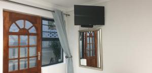 a flat screen tv on a wall next to a window at Emmaus Single Room in Bloemfontein