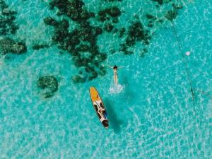 a person standing on a surfboard in the water at DAYA Beach, Lipe local in Ko Lipe