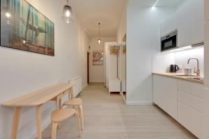 a kitchen with white cabinets and a wooden table at Laguna Centrum by Grand Apartments in Sopot +33 photos