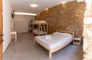 1 dormitorio con cama y pared de piedra en MARKOS LUXURY APARTMENTS en Koroni