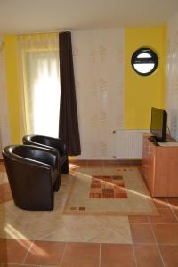 a living room with two chairs and a television at Udvarház Apartman in Mórahalom