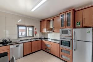 a kitchen with wooden cabinets and a white refrigerator at Apartamento 7 Mares in Sagres