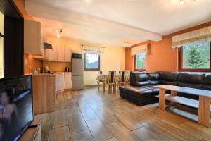 a living room with a leather couch and a kitchen at SŁONECZNE DOMKI in Istebna