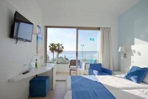 a hotel room with two beds and a desk and a window at BLUESEA Anba Romaní in Cala Millor