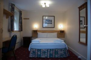 um quarto de hotel com uma cama, uma secretária e um espelho em Bridge Park Hotel em Londres