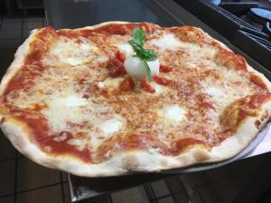 una pizza al formaggio con una foglia di basilico sopra di Albergo La Pineta a Cingoli