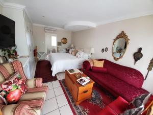 a bedroom with a bed and a living room with a couch at Gordon's Beach Lodge in Gordonʼs Bay