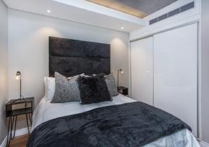 a bedroom with a large bed with a black headboard at Docklands Deluxe One bedroom Apartments in Cape Town
