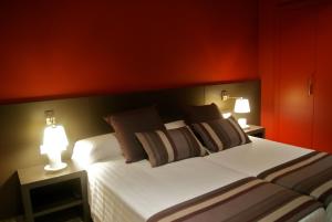 a bedroom with a large white bed with two lamps at Restaurante y Alojamiento Can Mach in Tapis