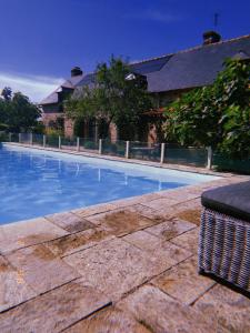 a large swimming pool with a trashcan next to a house at Tillac Chambres d'hôtes in Pléchâtel