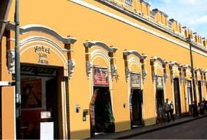 um edifício amarelo com arcos na lateral em Hotel San Jose em Mérida