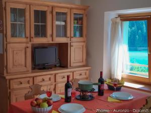 una cucina con tavolo, TV e alcune bottiglie di vino di 7home ad Auronzo di Cadore