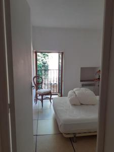 1 dormitorio con 1 cama, 1 silla y 1 ventana en Petit Gîte des Augustins, en Monflanquin