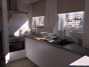 a white kitchen with a sink and a stove at Gezellig appartement voor het gezin in Middelkerke