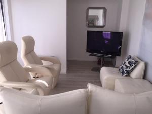 uma sala de estar com duas cadeiras brancas e uma televisão em Gezellig appartement voor het gezin em Middelkerke