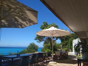a patio with tables and chairs and an umbrella at Ostria in Agios Nikitas