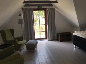 a bedroom with a bed and a chair and a window at Annagården Österlen in Kivik