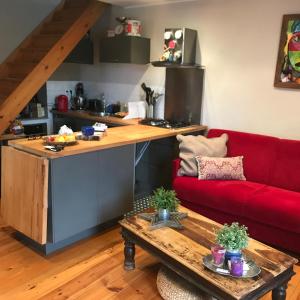 a living room with a red couch and a kitchen at Maison atypique in Brando