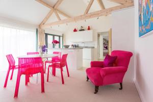 a dining room with red chairs and a table at The Cart Shed in Saxlingham