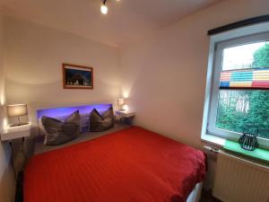 a bedroom with a red bed and a window at Ferienwohnungen Göhren in Göhren