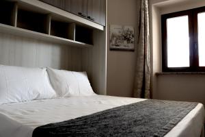 a bedroom with a bed with white sheets and a window at 13 Garden Rooms in Olbia
