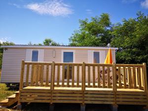 una casa pequeña con una gran terraza de madera con bandera en Nature Monchy, en Campneuseville