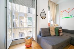 a living room with a couch and a large window at Apartamentos Moratín Las Letras in Madrid