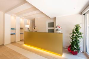 un vestíbulo con un mostrador amarillo y una planta en Hotel Corallo en Numana