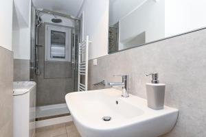 een badkamer met een witte wastafel en een spiegel bij Gorgeous Trastevere loft on the river in Rome +25 foto's