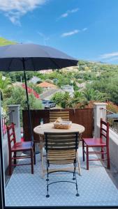 d'une table, de chaises et d'un parasol sur le balcon. dans l'établissement Maison atypique, à Brando