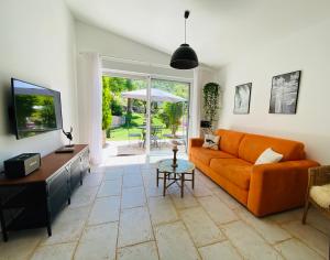een woonkamer met een oranje bank en een televisie bij Maison de vacances Villa Cardabella in Le Tignet