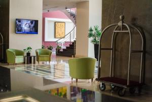 a lobby with green chairs and a luggage cart at Hesperia WTC Valencia in Valencia