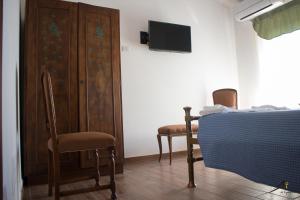 a bedroom with a bed and two chairs and a tv at La Gazza in Viterbo