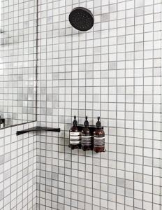 three alcohol bottles on a tiled wall in a shower at Hotel June, Los Angeles, a Member of Design Hotels in Los Angeles