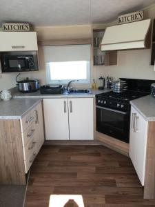 a kitchen with white cabinets and a black stove at G17 The Chase , Ingoldmells, Skegness in Ingoldmells