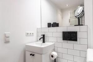 ein weißes Badezimmer mit einem Waschbecken und einem Spiegel in der Unterkunft Oma Lieschen in Keitum