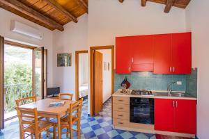 una cocina con armarios rojos y una mesa con sillas. en Casa Gallizza con vista mare by Wonderful Italy en Cefalú