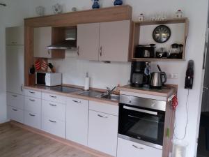 cocina con armarios blancos, fregadero y fogones en Ferienhaus Am Barenberg en Thülsfeld