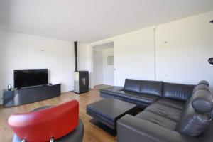 sala de estar con sofá negro y silla roja en Villa de l'albatros Sables d'or en Plurien