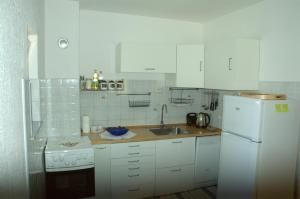 a white kitchen with a sink and a refrigerator at Apartman Juka in Krasno Polje