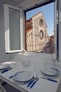 a table with plates and glasses and a window with a church at Central Apartments Integrated Hotel in Zadar