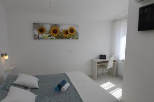 Ein weißes Zimmer mit einem Bett, einem Tisch und einem Bild. in der Unterkunft Apartments Mareblu in Rabac