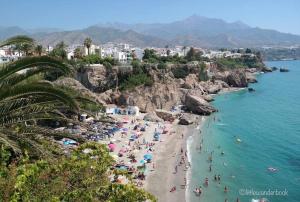 a group of people on a beach in the water at Chez Alison! Central nerja apt in Nerja