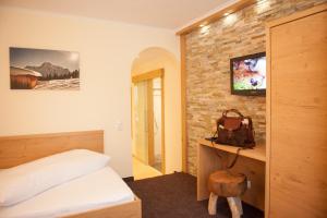 a bedroom with a bed and a tv on a brick wall at Pension Iris in Lech am Arlberg