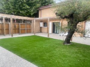 a green yard with a tree in front of a building at Le Bertomiu in Parentis-en-Born